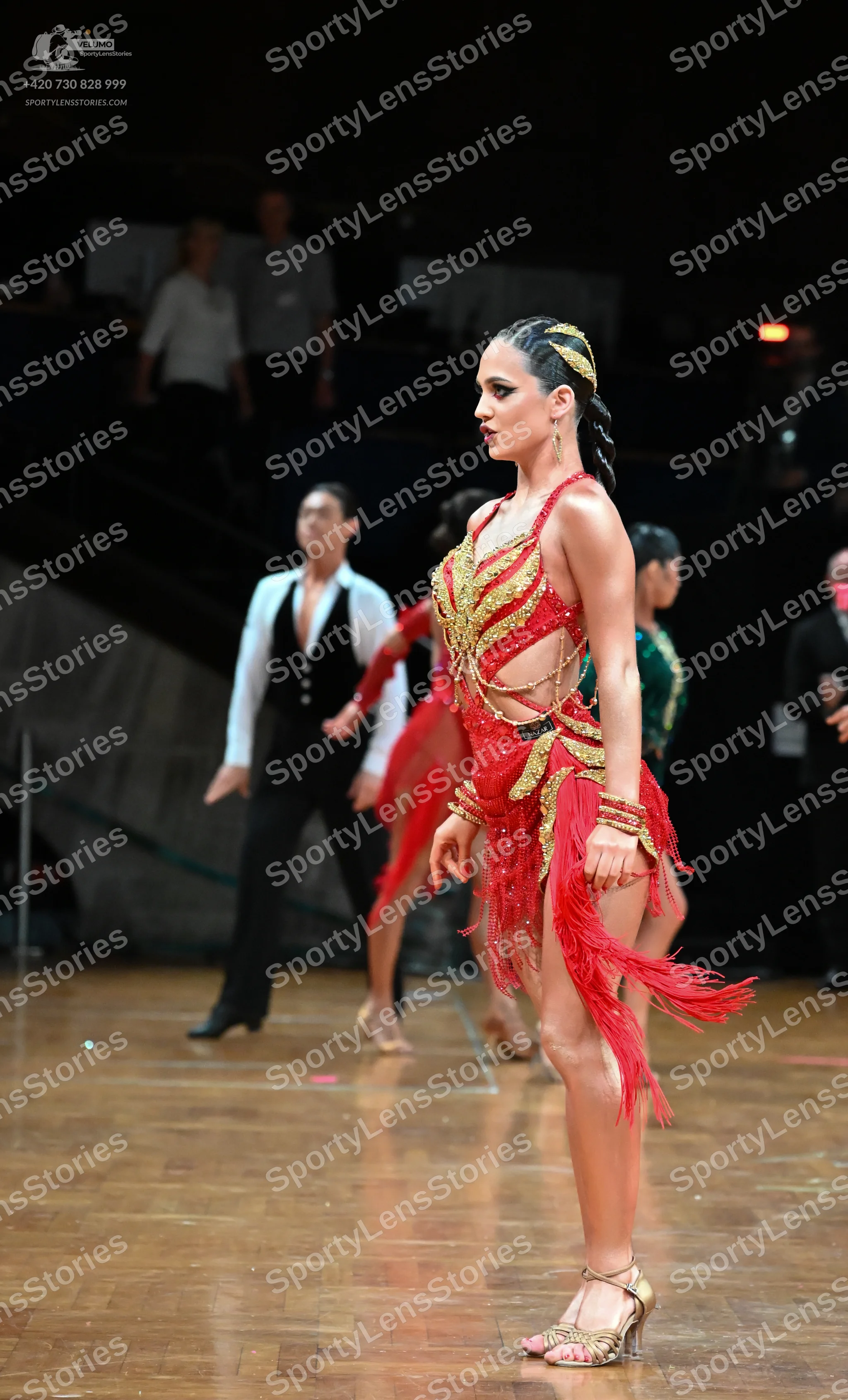 Dancesport competitor: Main female dancer: red Latin dress with gold sequin embellishments and long red