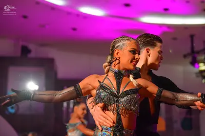 Dancesport competitor: Female dancer: black Latin dance costume with heavy silver/metallic sequin and b