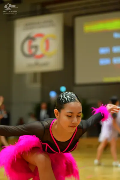 Dancesport competitor: Female dancer in foreground: black long-sleeved Latin dance costume with bright 