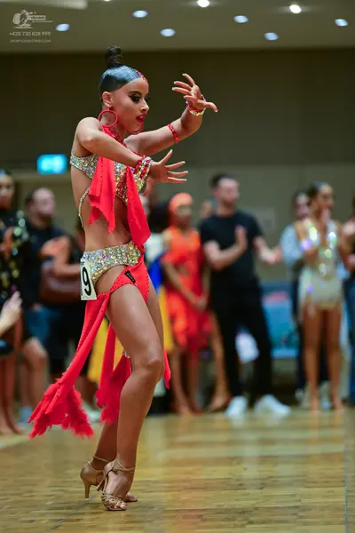 Dancesport competitor: Main female dancer: red latin dress with fringe and multicolored sequins, red ho