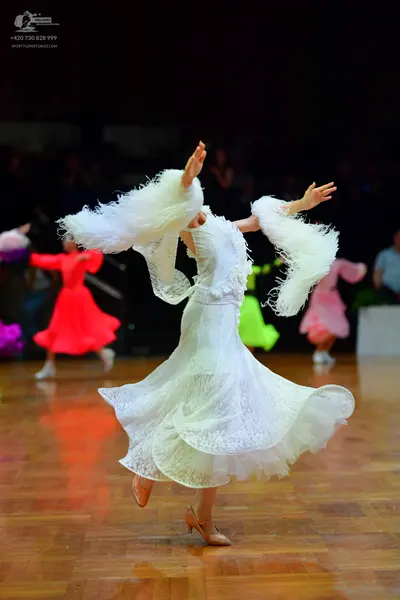 Dancesport competitor: Main female dancer: white ballroom dress with lace-like fabric, a voluminous lay