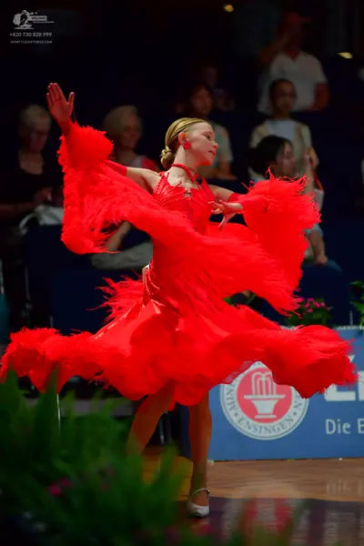 Dancesport competitor: Female dancer: bright red Latin dress with voluminous red feathers or fringe