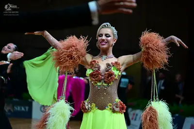 Dancesport competitor: Female dancer in foreground: lime green and tan Latin dance dress with a sequine