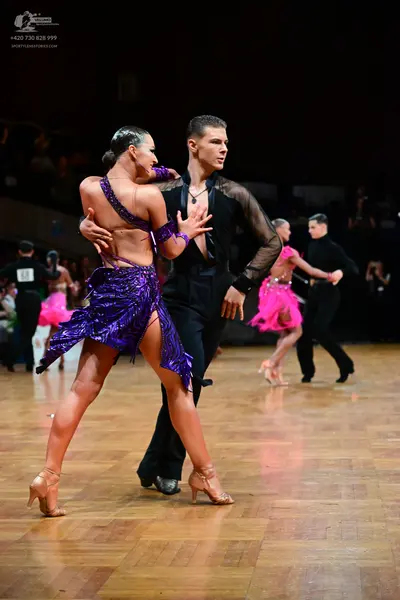 Dancesport competitor #56: Female dancer in foreground: purple sequined Latin dress with thin straps
