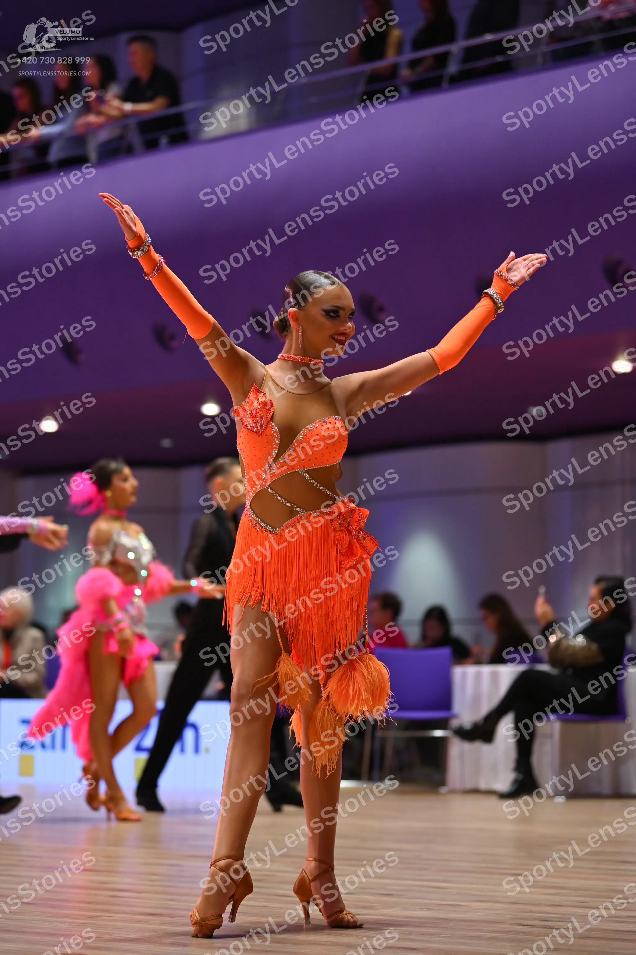 Dancesport competitor: Main female dancer: orange latin dress with sequins, mesh, and fringe, with matc
