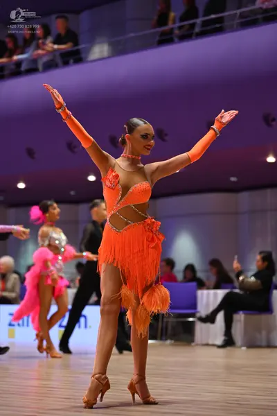 Dancesport competitor: Main female dancer: orange latin dress with sequins, mesh, and fringe, with matc