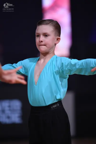 Dancesport competitor: Dancer: light blue long-sleeved top with a deep V-neckline and black trousers wi