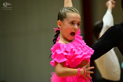 Dancesport competitor: Female dancer: bright pink Latin dress with large ruffles on the bodice and pink