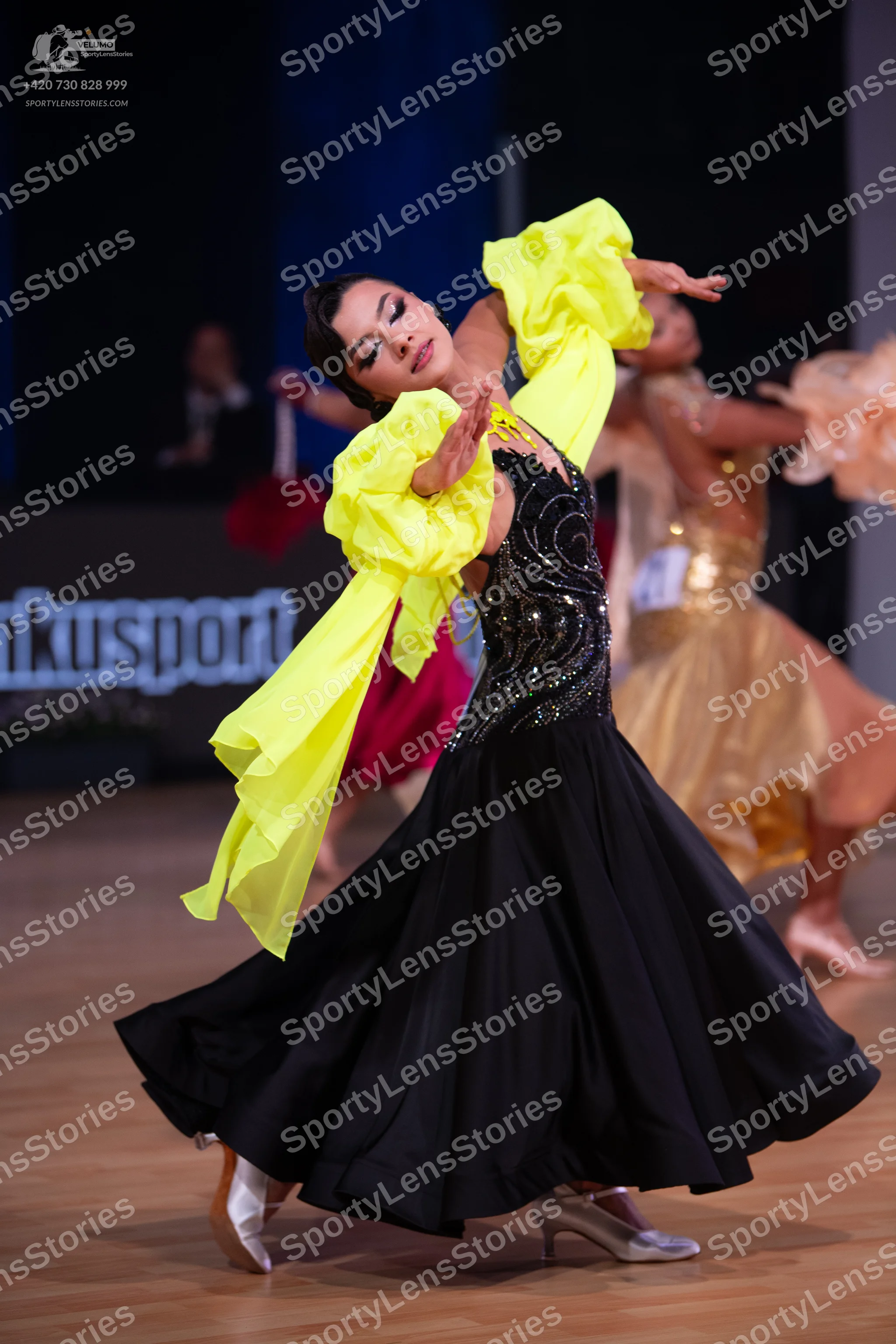 Dancesport competitor: Main female dancer: black ballgown with a heavily sequined bodice and large, vol