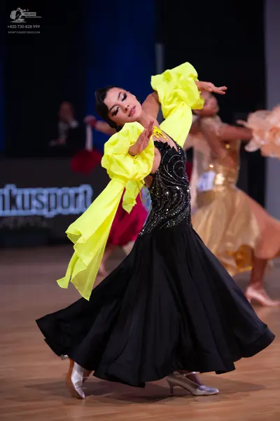 Dancesport competitor: Main female dancer: black ballgown with a heavily sequined bodice and large, vol