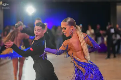 Dancesport competitor: Female dancer (left foreground): black long-sleeved latin dance top with blue se