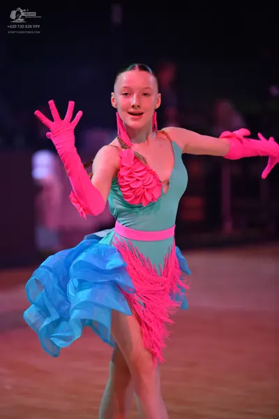 Dancesport competitor: Female dancer: teal Latin dance dress with pink waistband, large pink ruffled fl