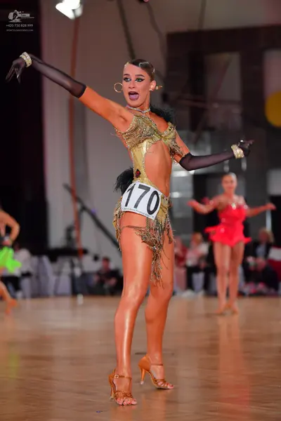 Dancesport competitor #170: Female dancer in foreground: gold Latin dance costume with sequins and fringe, a