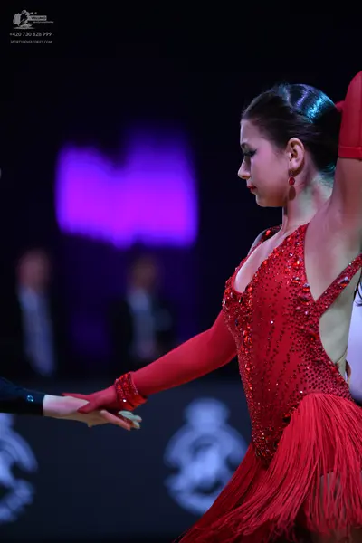 Dancesport competitor: Female dancer: red latin dress with sequins and fringe, featuring a long sleeve 