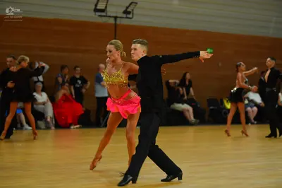 Dancesport competitor: Central female dancer: gold sequin crop top and pink skirt
