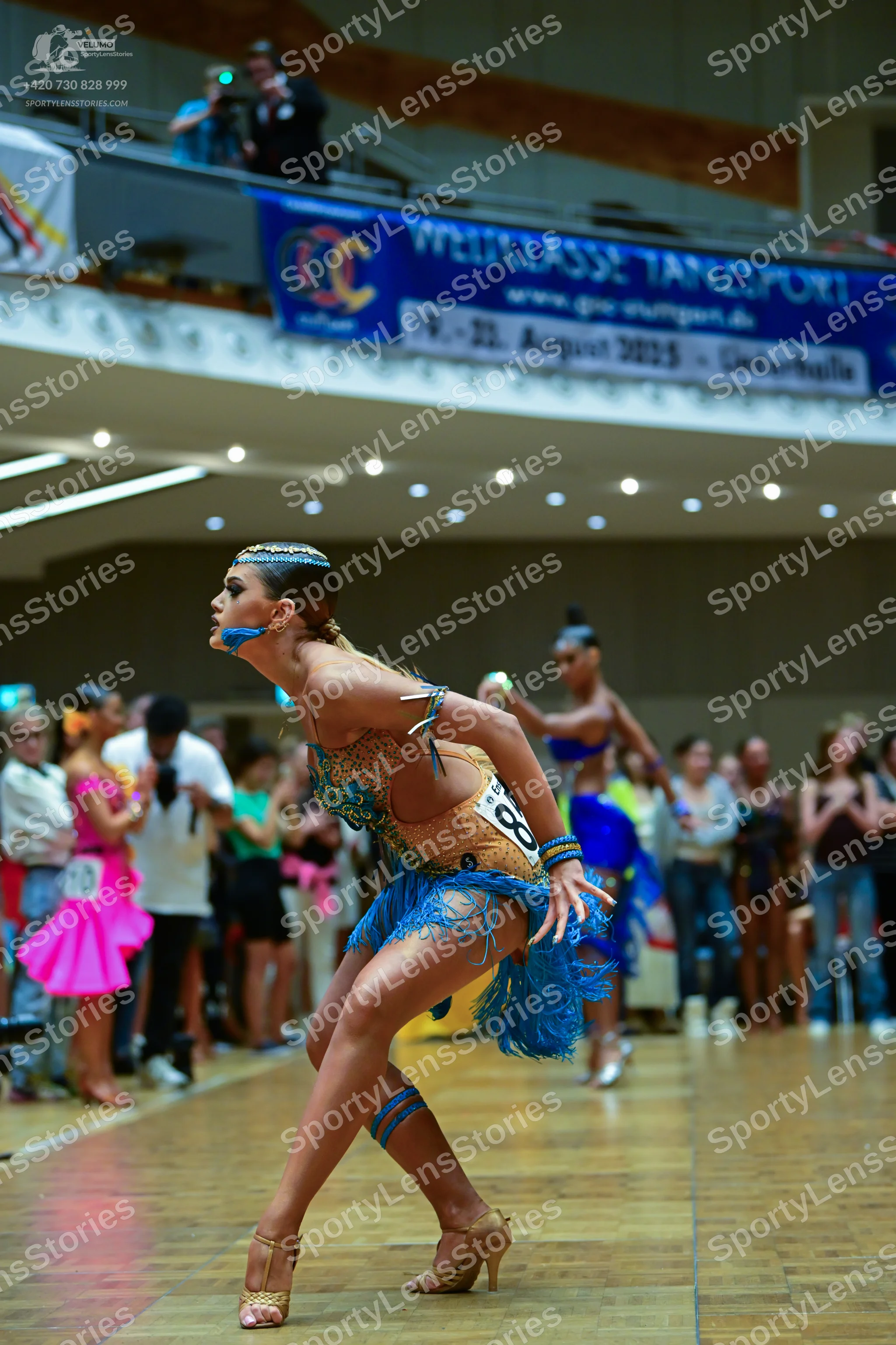 Dancesport competitor: Main dancer: bronze/gold sequined Latin dress with bright blue fringe, blue leg