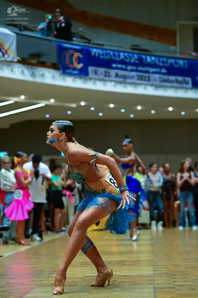 Dancesport competitor: Main dancer: bronze/gold sequined Latin dress with bright blue fringe, blue leg 
