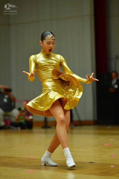 Dancesport competitor: Female dancer: gold latin dress with long sleeves and a ruffled skirt, made of s
