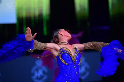Dancesport competitor: Female dancer: blue Latin dress with a gold and bronze sequined bodice and sheer
