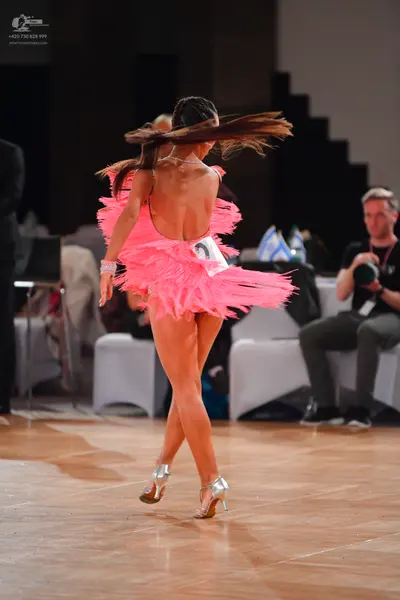 Dancesport competitor: Female dancer: pink latin dress with layers of fringe and a backless design, pai