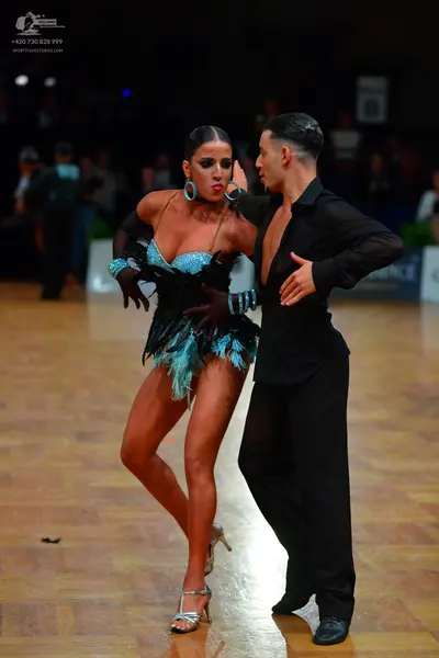 Dancesport competitor: Female dancer: teal and black latin dress with feather-like fringe and sequins, 
