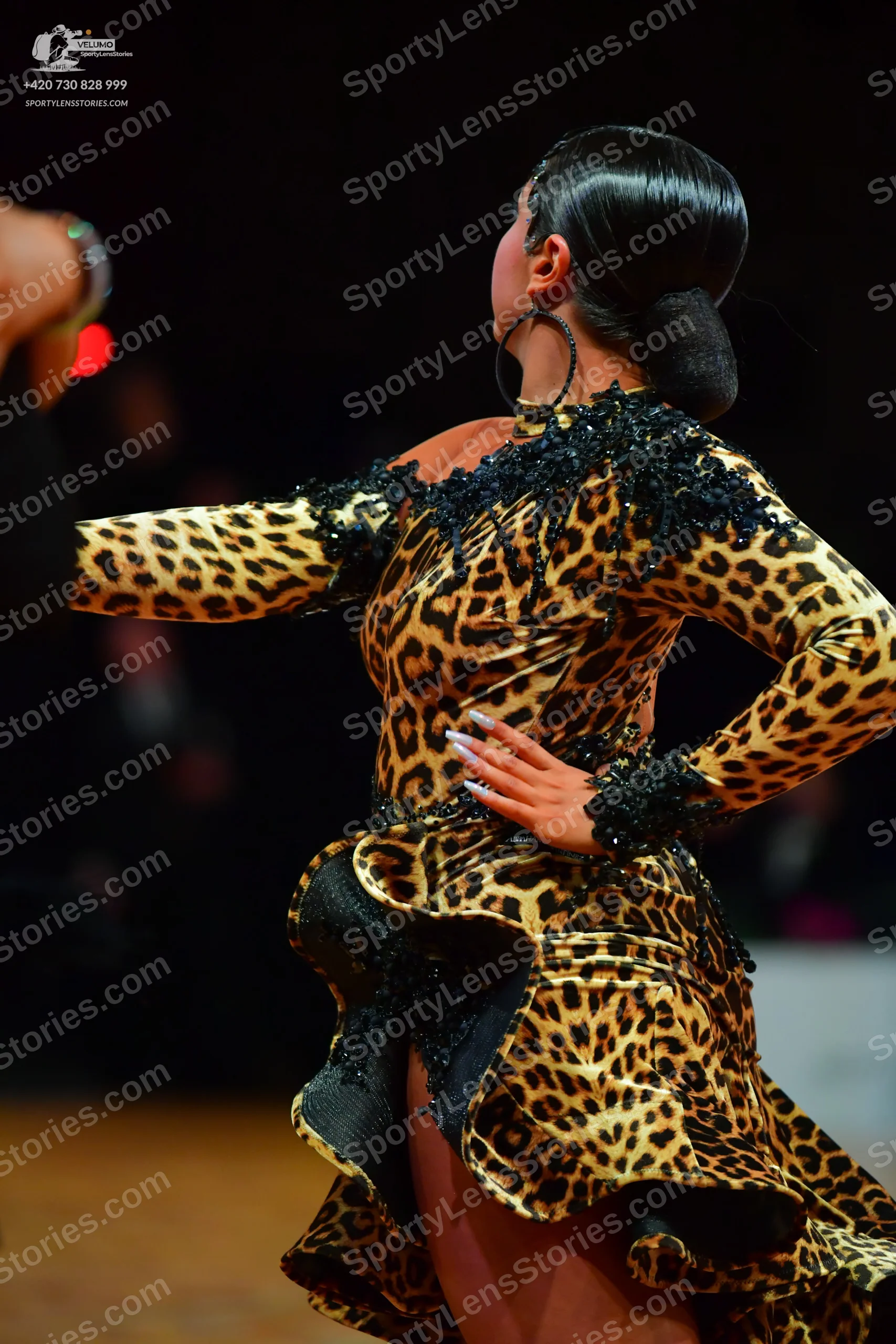 Dancesport competitor: Female dancer: leopard-print Latin dress with long sleeves, featuring black sequ