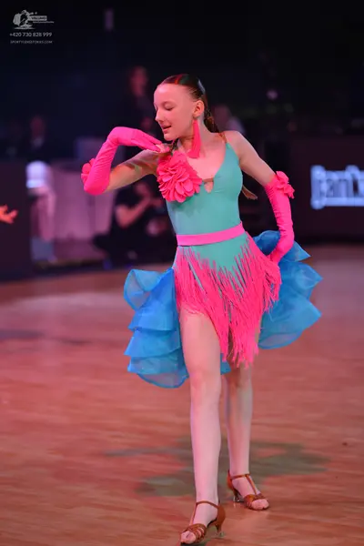 Dancesport competitor: Female dancer: teal Latin dance dress with a bright pink floral detail on the bo