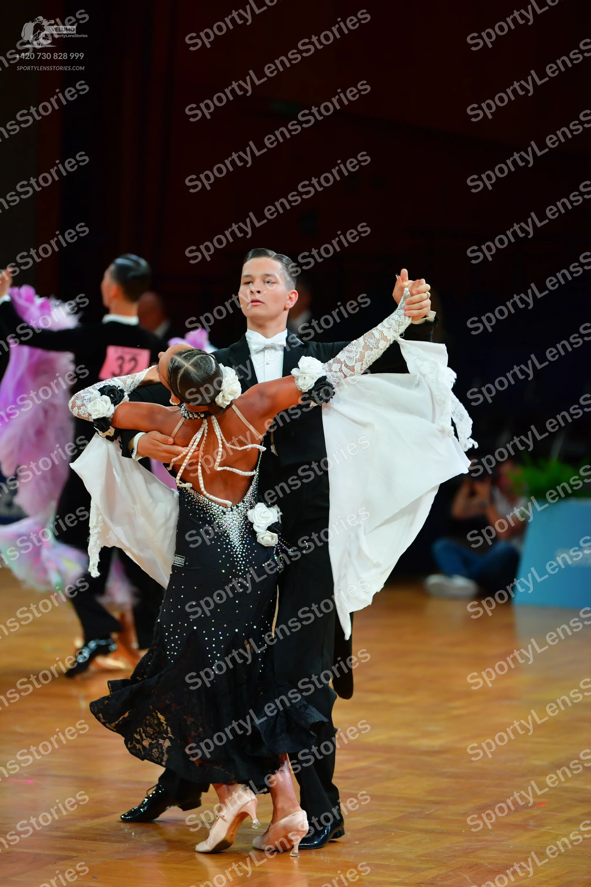 Dancesport competitor: Male dancer (center): black suit, white shirt, and black bow tie