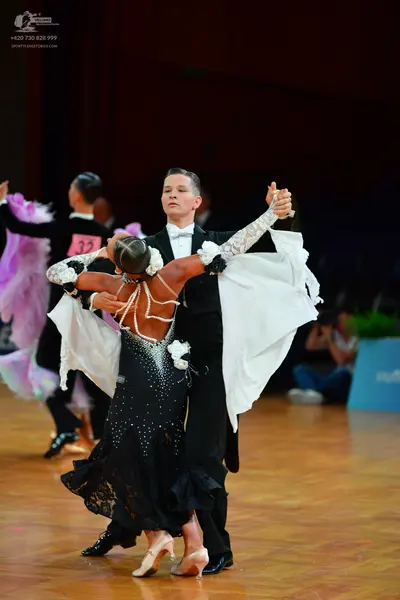Dancesport competitor: Male dancer (center): black suit, white shirt, and black bow tie