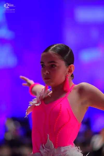 Dancesport competitor: Female dancer: neon pink Latin dance bodysuit with white feather/floral decorati