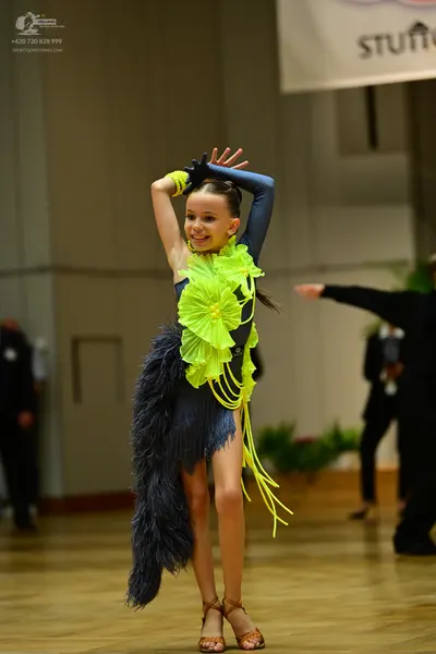 Dancesport competitor: Female dancer: navy blue Latin dance dress with lime green ruffles on the bodice