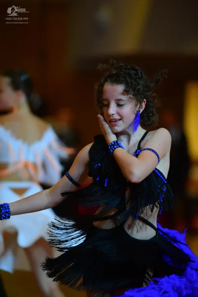 Dancesport competitor: Female dancer in foreground: black latin dress with blue sequin accents and blac
