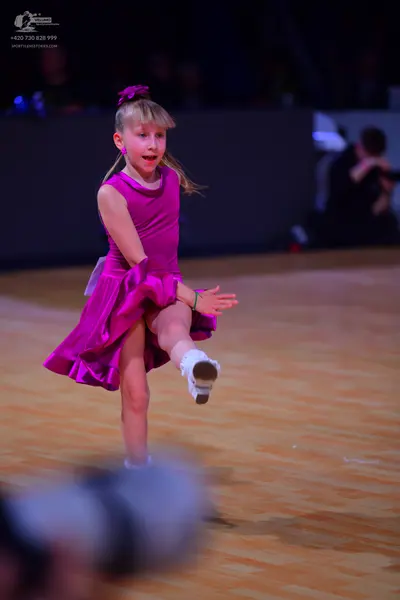 Dancesport competitor: Female dancer: bright pink sleeveless dress with a flared skirt and a pink flowe