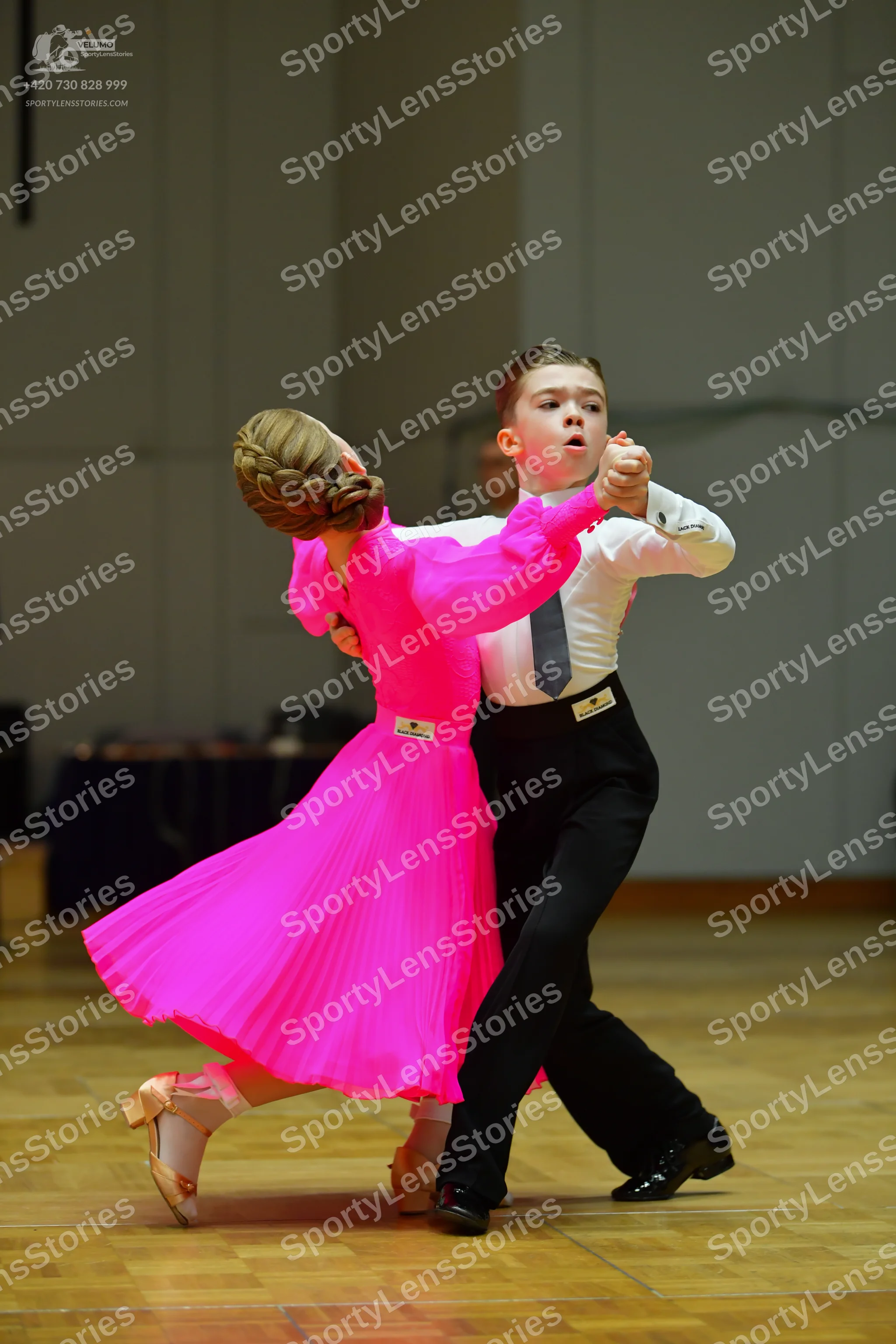 Dancesport competitor: Female dancer: bright pink long-sleeved ballroom dress with a flowing pleated sk