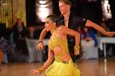 Dancesport competitor: Female dancer: yellow sequin latin dress with cutouts and a fringe skirt, gold h
