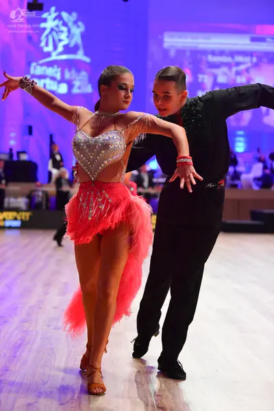 Dancesport competitor: Female dancer: silver sequined halter-style top with fringe and a short pink fri