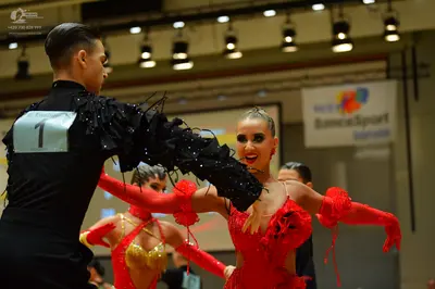 Dancesport competitor: Male dancer: black long-sleeved shirt with black feathered or fringed sleeve det