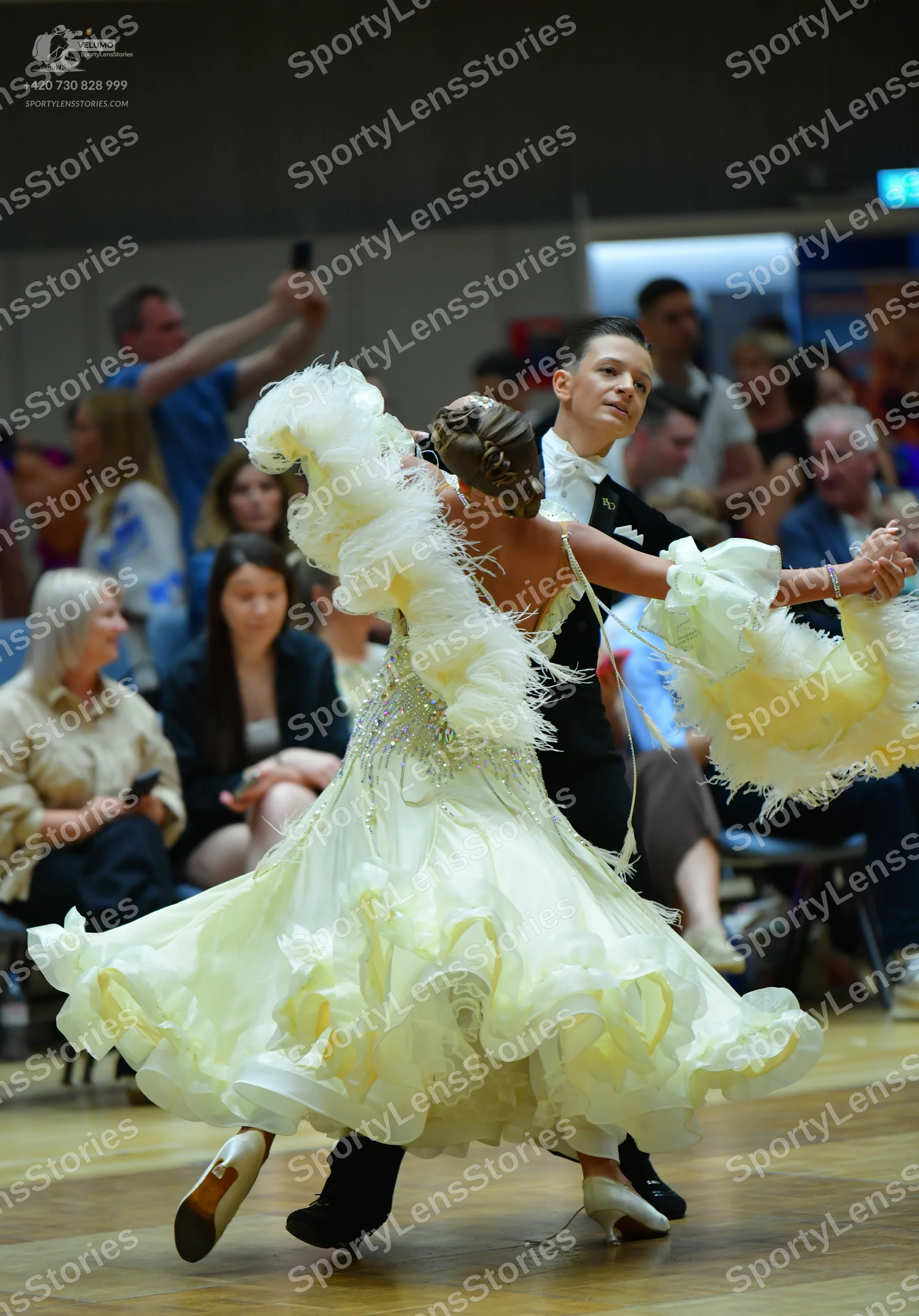 Dancesport competitor: Female dancer: voluminous pale yellow/cream ballgown with ruffled layers, sequin