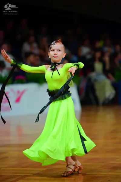 Dancesport competitor: Female dancer: lime green ballroom gown with a black waistband and long black ri