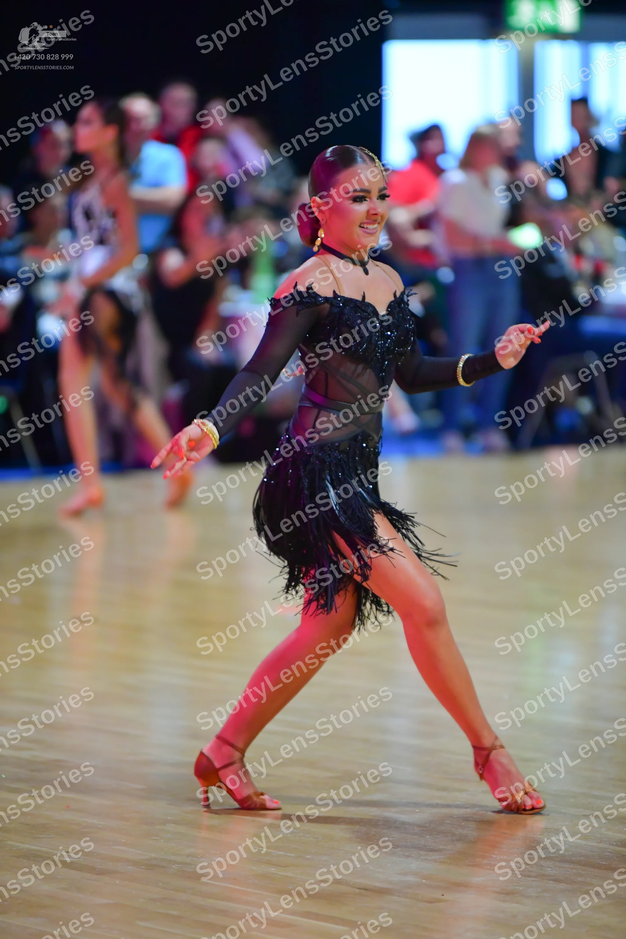 Dancesport competitor: Female dancer (center): black Latin dress with sheer long sleeves, an embellishe