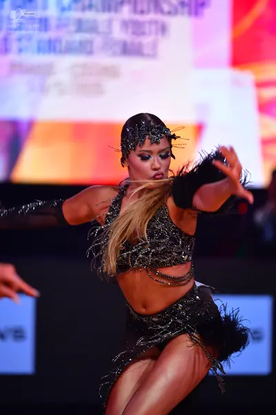 Dancesport competitor: Female dancer: black latin dance costume with sequins and long, thin fringe/stra