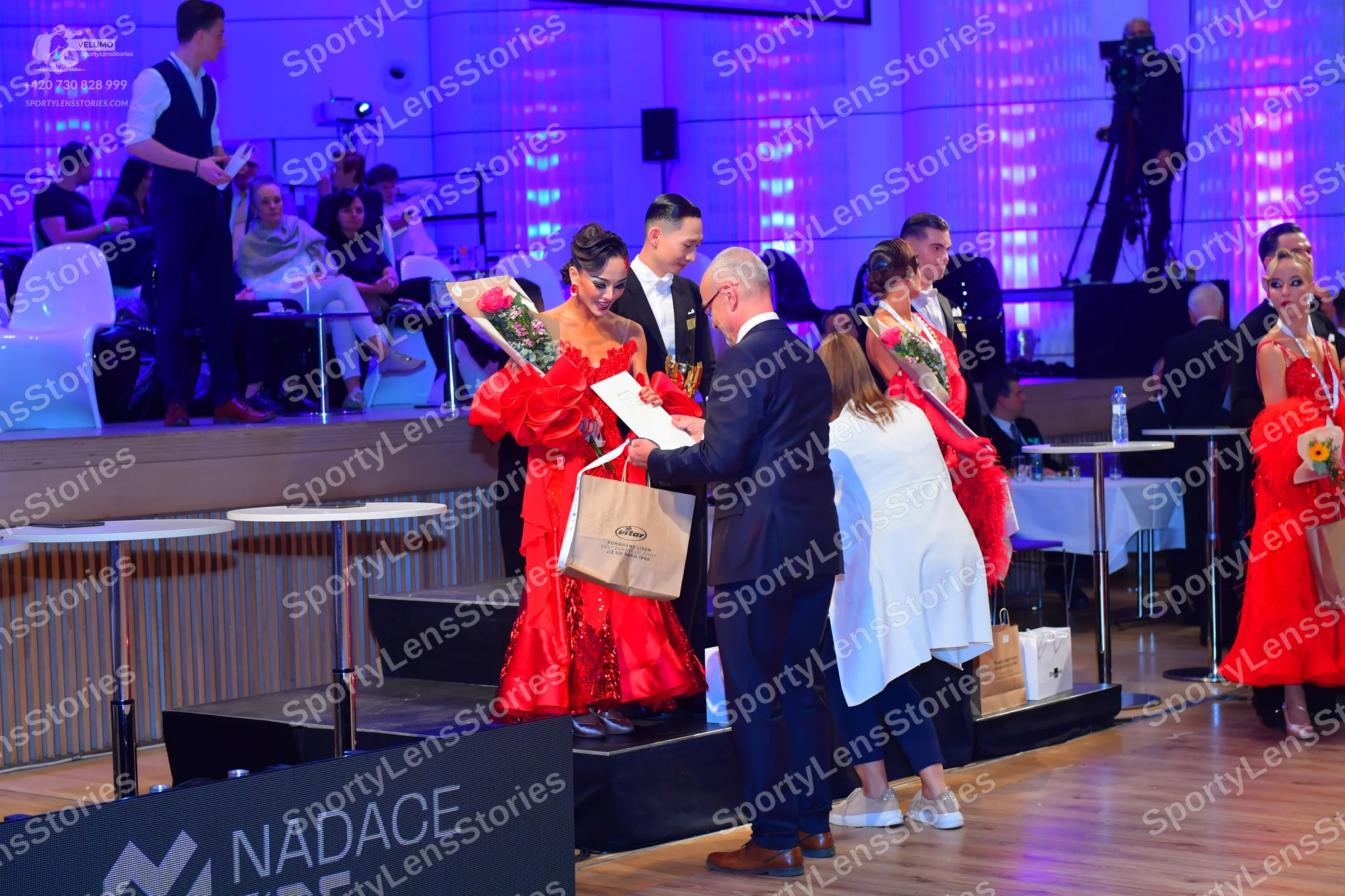 Dancesport competitor: Female dancer (left): Red voluminous ballroom-style dress with ruffled or lace f