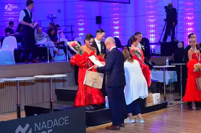 Dancesport competitor: Female dancer (left): Red voluminous ballroom-style dress with ruffled or lace f