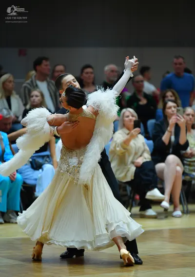 Dancesport competitor: Female dancer: cream-colored ballgown with a sequined bodice, a large white feat