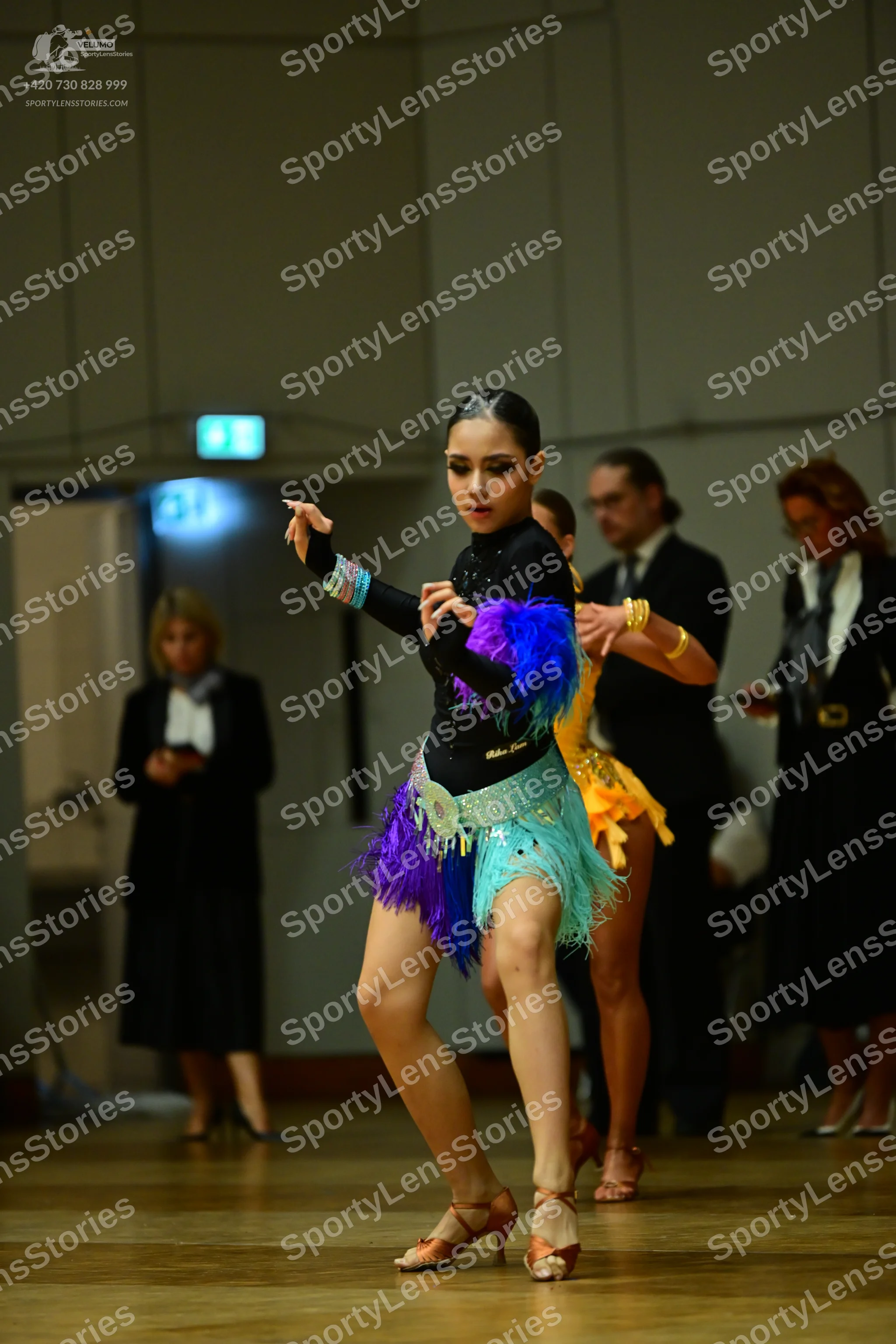 Dancesport competitor: Female dancer 1: black long-sleeved latin dress with colorful fringe (blue, purp