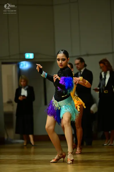 Dancesport competitor: Female dancer 1: black long-sleeved latin dress with colorful fringe (blue, purp