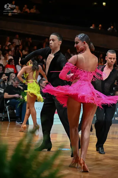 Dancesport competitor: Male dancer (center): black long-sleeved shirt with a deep V-neck and black trou