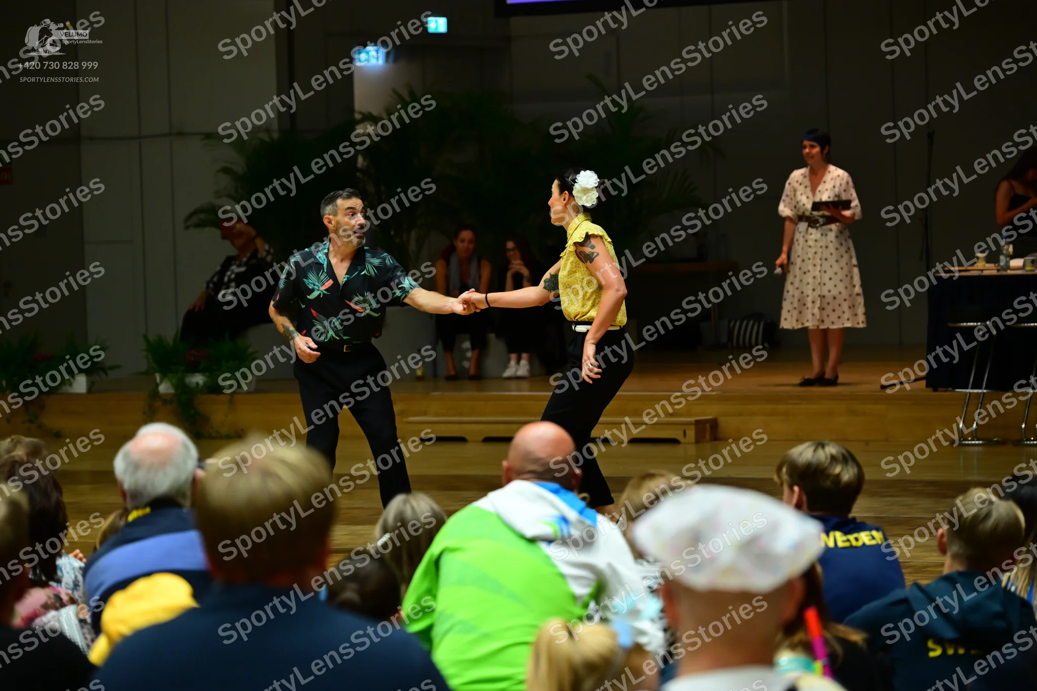 Dancesport competitor: Male dancer: black short-sleeved shirt with a green and teal floral pattern and