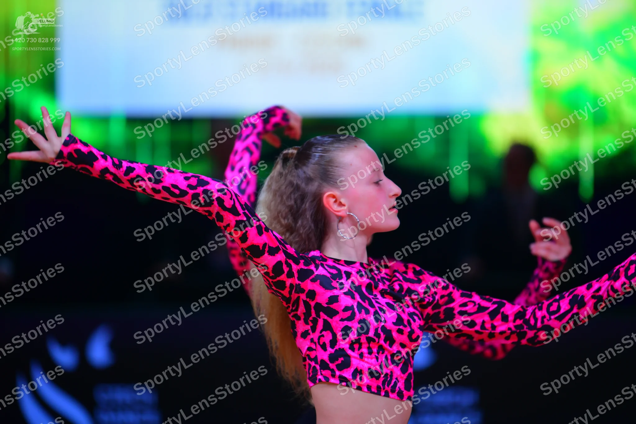 Dancesport competitor: Female dancer: bright pink crop top with black leopard print pattern