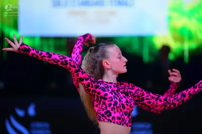Dancesport competitor: Female dancer: bright pink crop top with black leopard print pattern